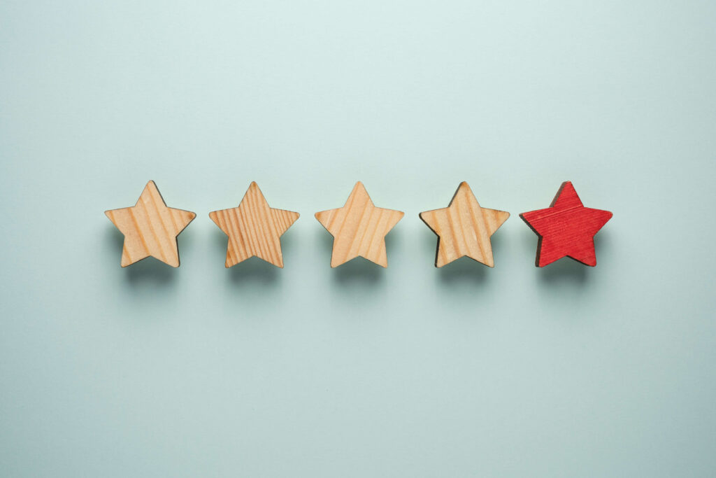 Four wooden stars with one red star on a pale blue background