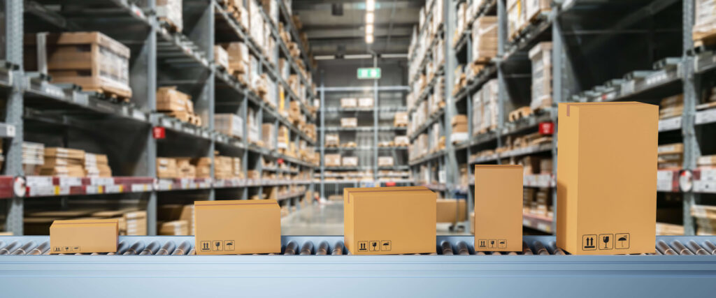 Different sized boxes on a conveyor belt in a warehouse with boxes behind them Voordelen van een snelle voorraadrotatie