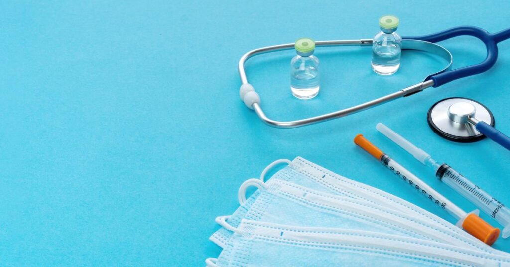 Blue background showing a stethoscope, syringes and medical masks medical supply industry challenges and solutions