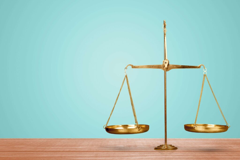 Gold traditional balance scales on a wooden table in front of a blue wall the pros and cons of ERP upgrade versus ERP replacement