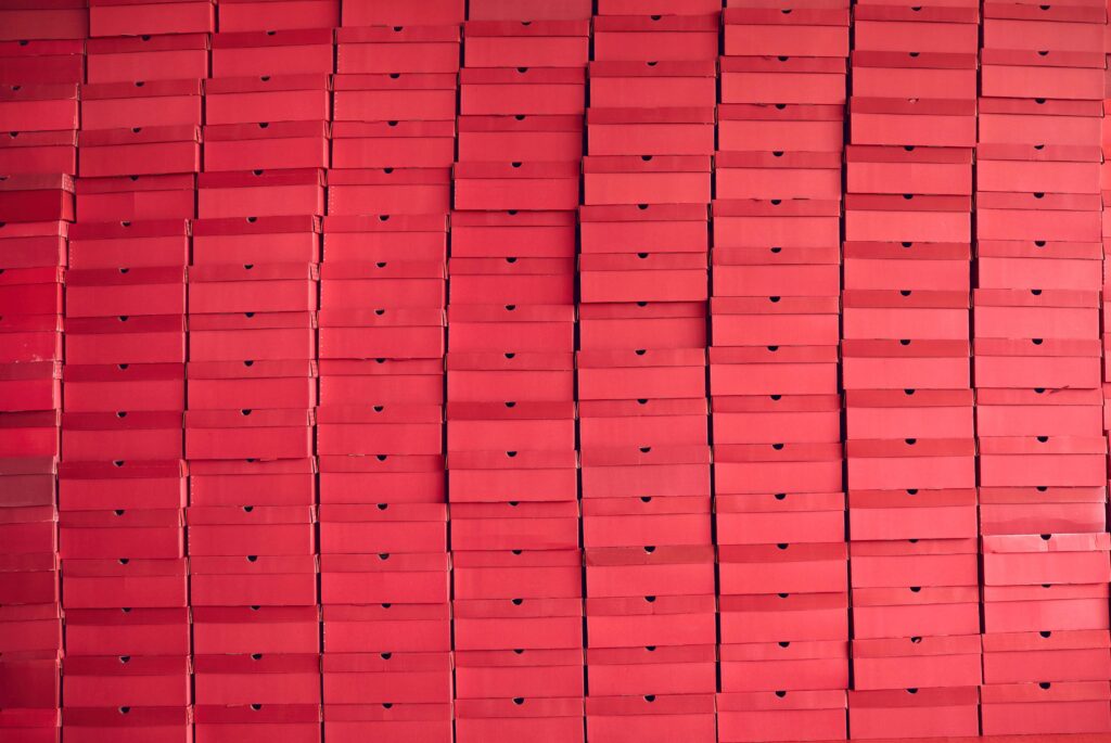 Background of multiple red cardboard package boxes stacked at a factory warehouse. the problem with excess stock disadvantages of excess inventory