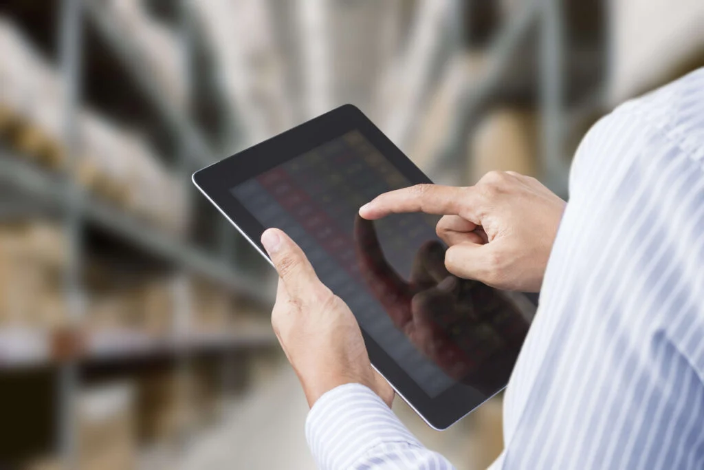 A close up of a man holding a laptop in a warehouse inventory management techniques
