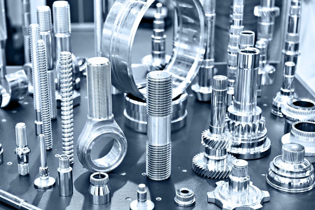 A variety of metal screws, fixtures and fittings all silver spread out standing up on a metal surface to show bill of materials