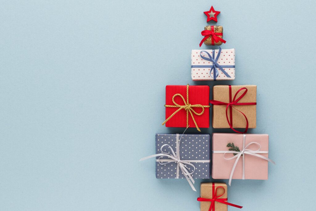 Presents stacked flat on a pale blue background to represent a Christmas tree seasonal sales seasonal forecasting