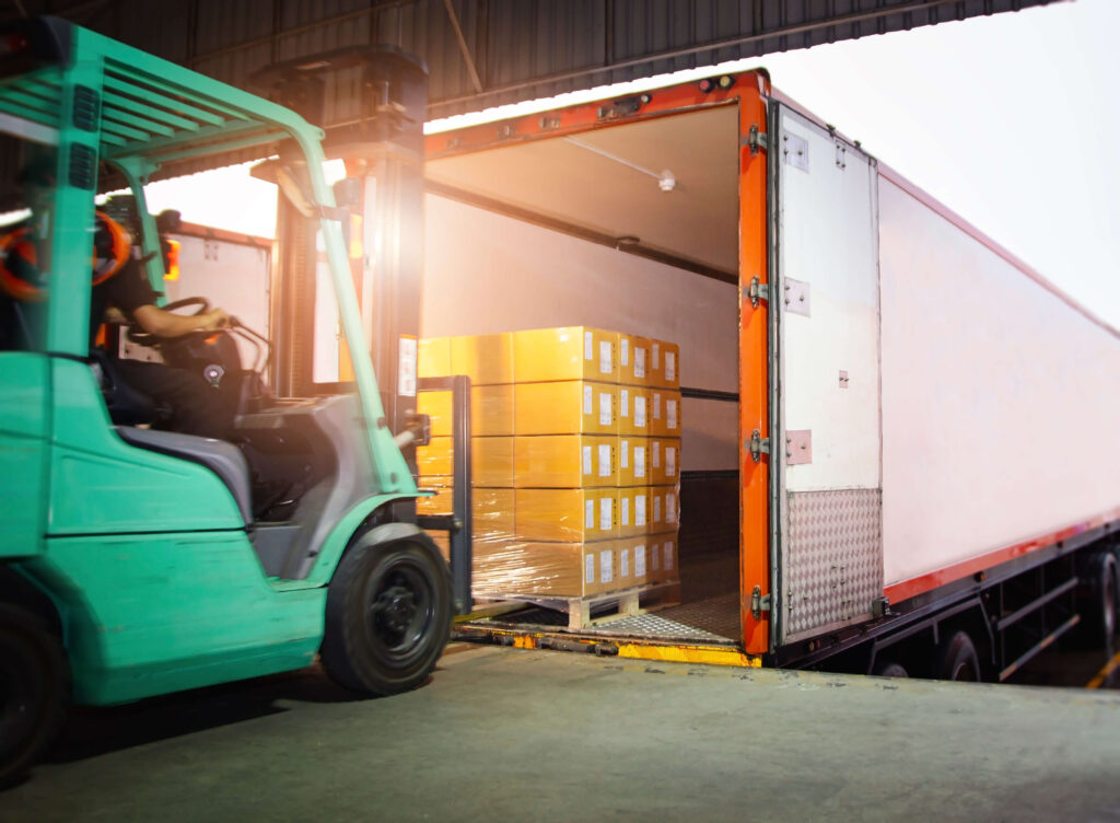 Forklift Tractor Loading Package Boxes into Cargo Container at a warehouse