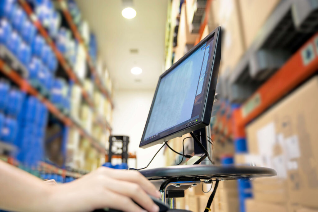 Computer in a warehouse with blurred background of stock on shelves.