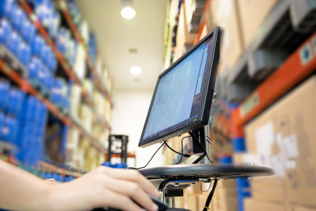 Computer in a warehouse Blurred background of stock on shelves. Eenvoudig en goed voorraadbeheer