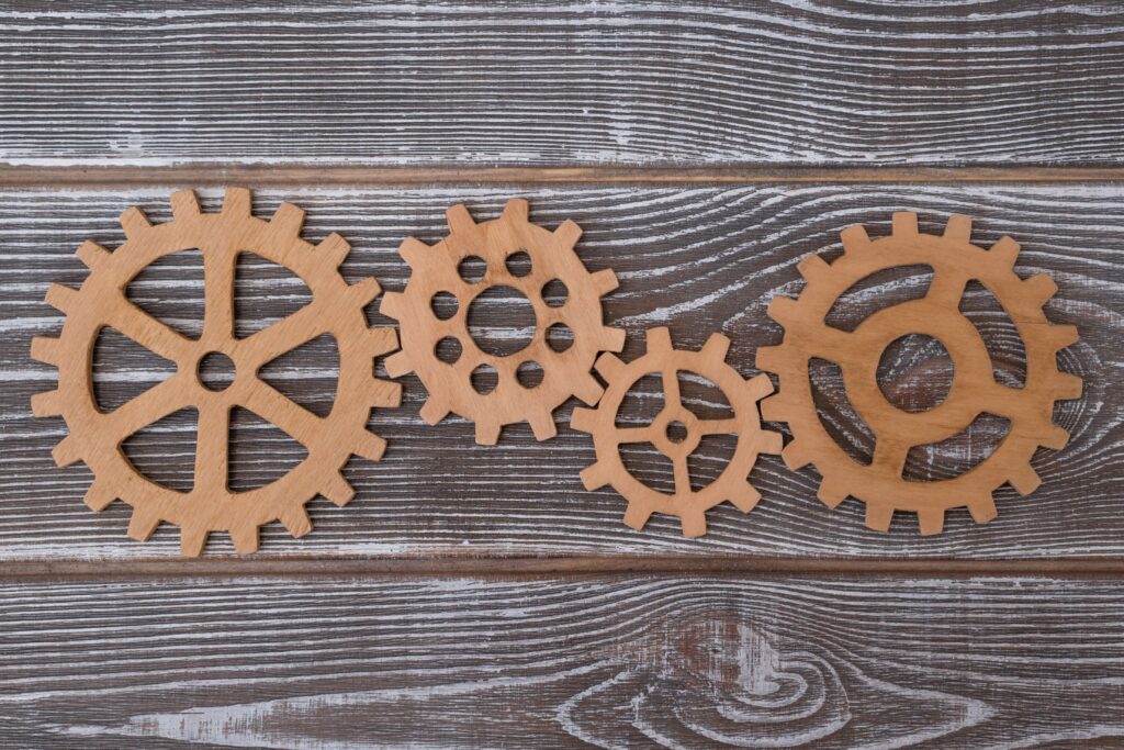 Four wooden cogs of different sizes on a wooden table to show supply chain resilience and optimisation