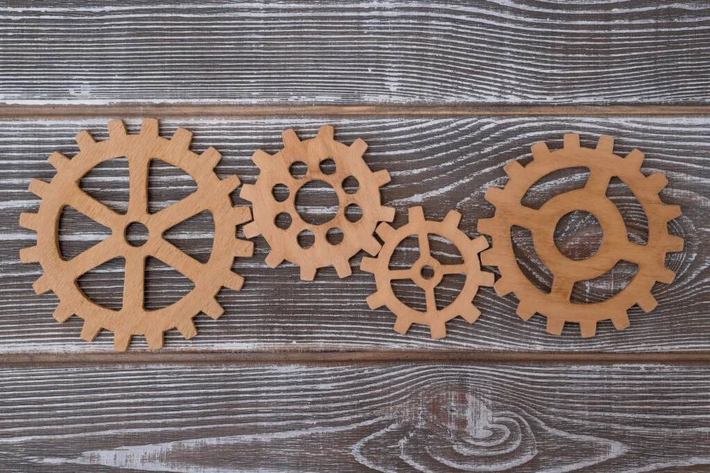 Four wooden cogs of different sizes on a wooden table to show supply chain resilience and optimisation
