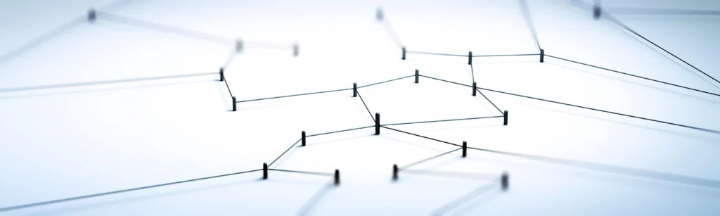 Multiple pins stuck into a light table connected with string to show supply chains