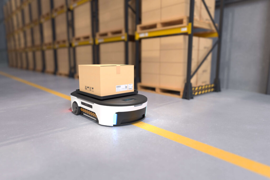 A low automated guided cart following a yellow line around a warehouse with a box on top next to a rack of shelving with boxes warehouse technology and supply chain management