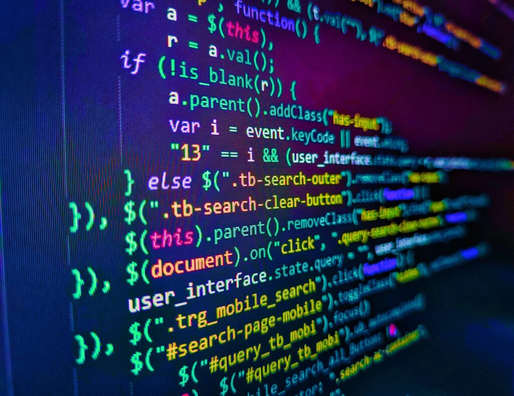 A close up of a computer screen at an angle showing rows of code in different coloured text to show software