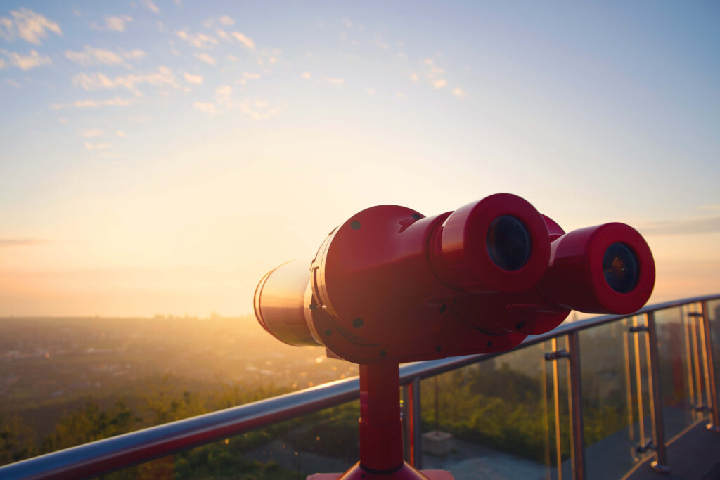 Red binoculars at a lookout point looking over the horizon as the sun is rising demand planning and forecasting