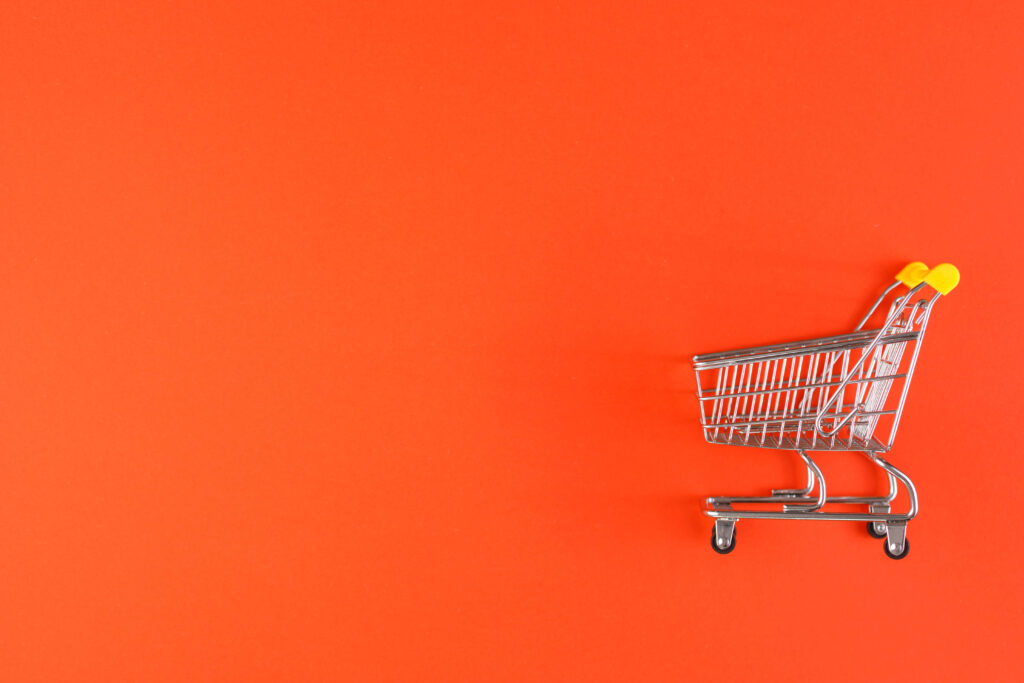 Metal shopping trolley with a yellow handle on a red background