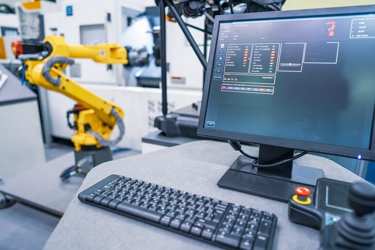 Roboterarm neben einem Computerbildschirm in einer Fabrik Automatisierung und Transparenz der Lieferkette