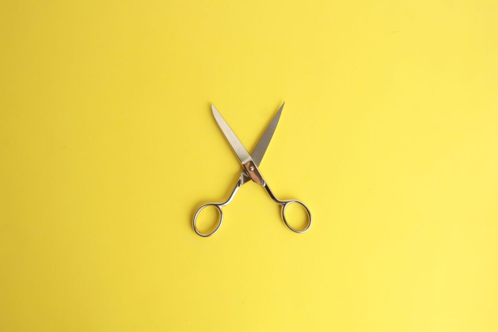 Silver scissors open on a yellow background why cutting software budgets could cost you more in the long run