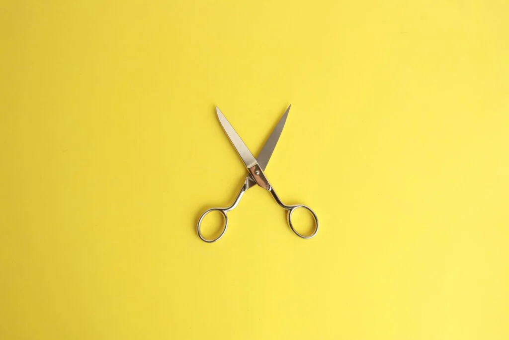 Silver scissors open on a yellow background why cutting software budgets could cost you more in the long run