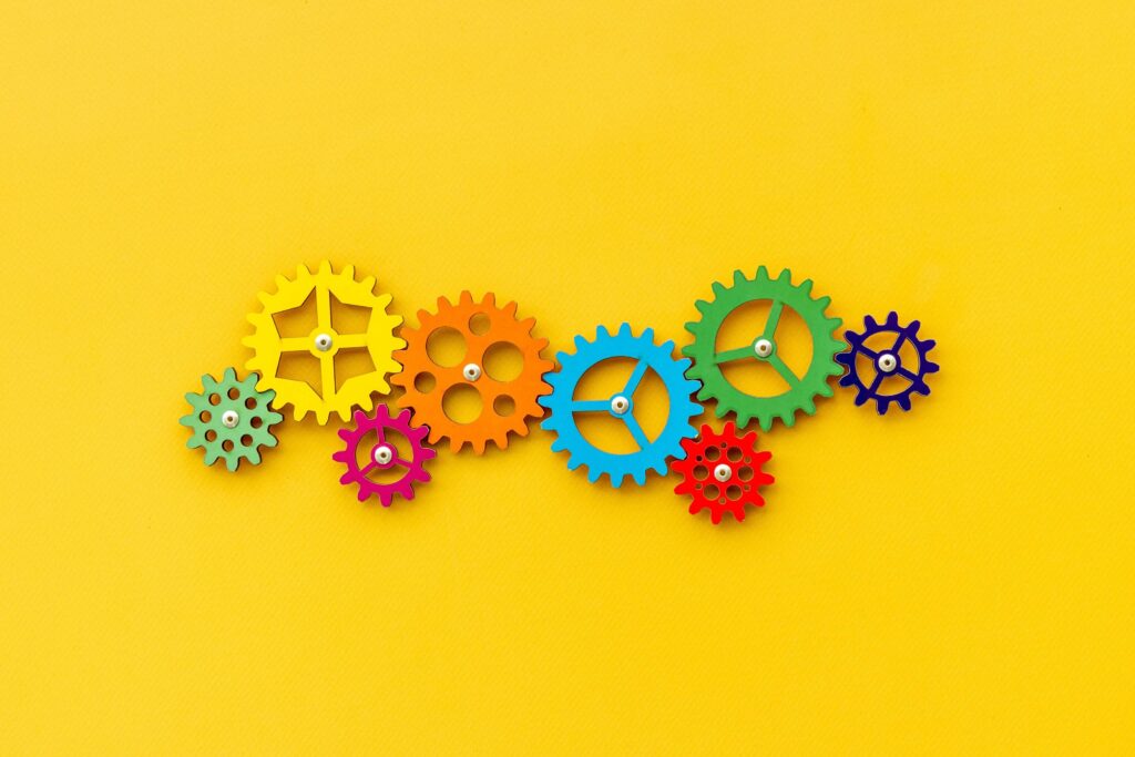 Different coloured cogs of different sizes connected on a yellow background supply chain risk mitigation strategies supply chain risk strategies