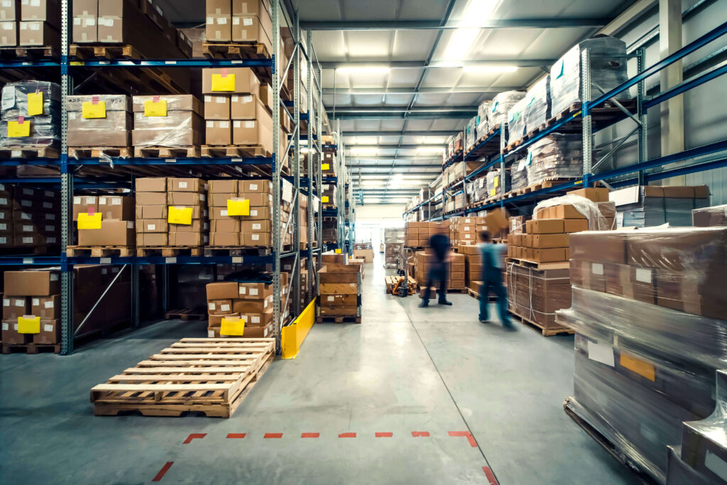 A warehouse with boxes on the racking and people moving boxes warehouse analysis inventory planning