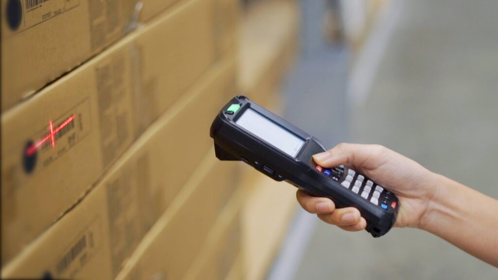 Hand-held scanner scanning a box in a warehouse inventory control techniques