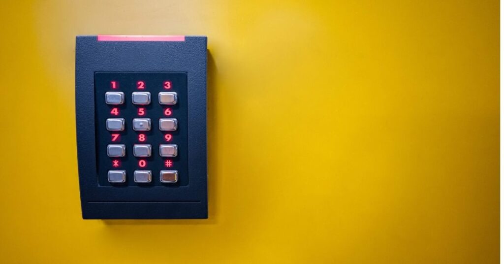 En dörrkodlås på en gul vägg, visar säkerhetskontroll för ISO 27001. 