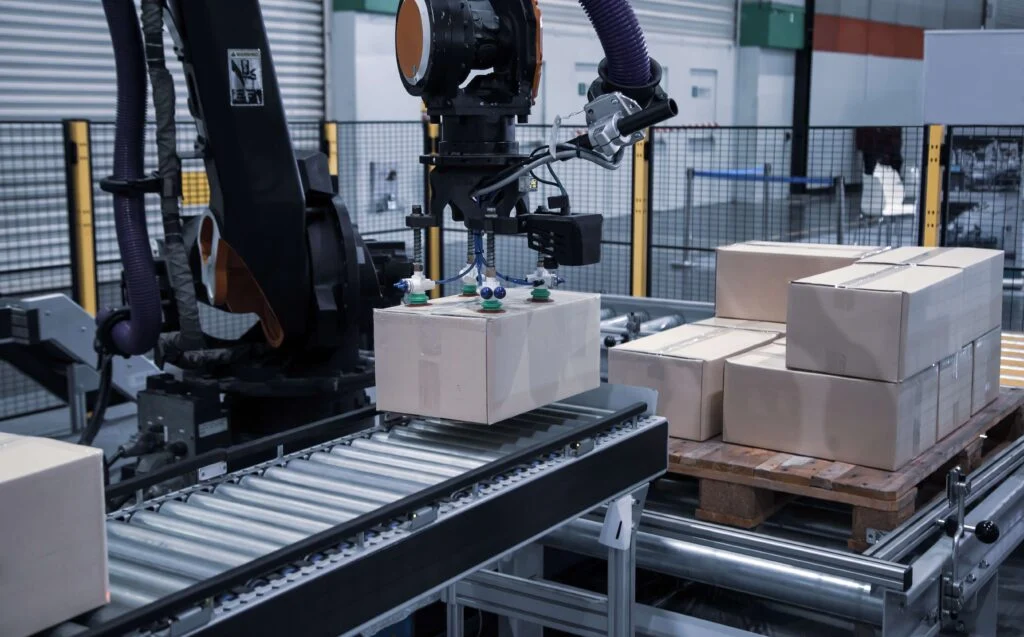 Industrial robot arm loading carton on conveyor in a factory. Supplier order calendars